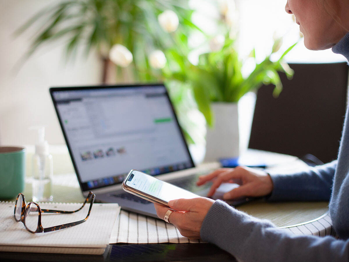 Person reading a cellphone while using a laptop